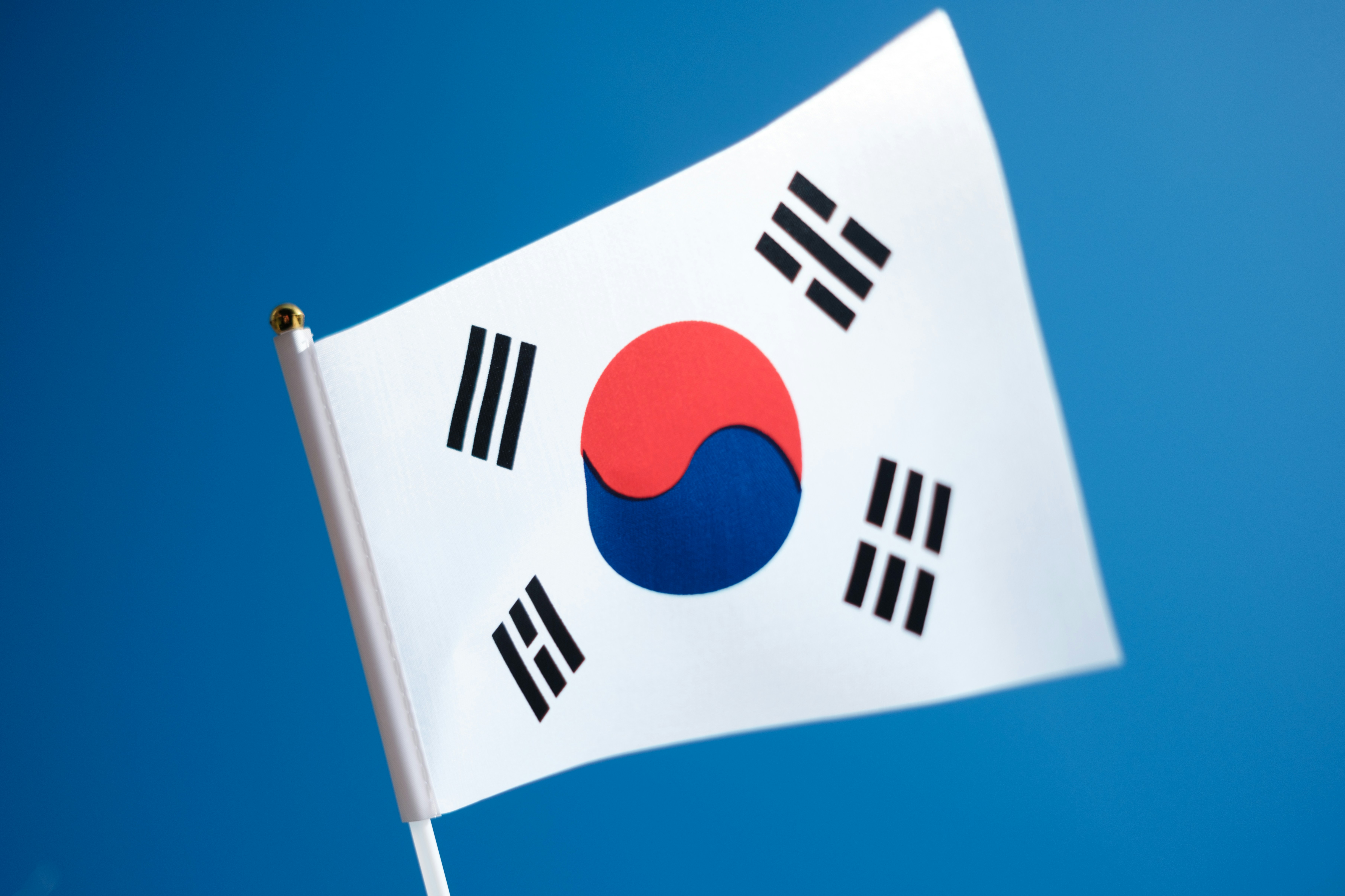 The flag of South Korea flies on a sunny day against a clear blue sky.